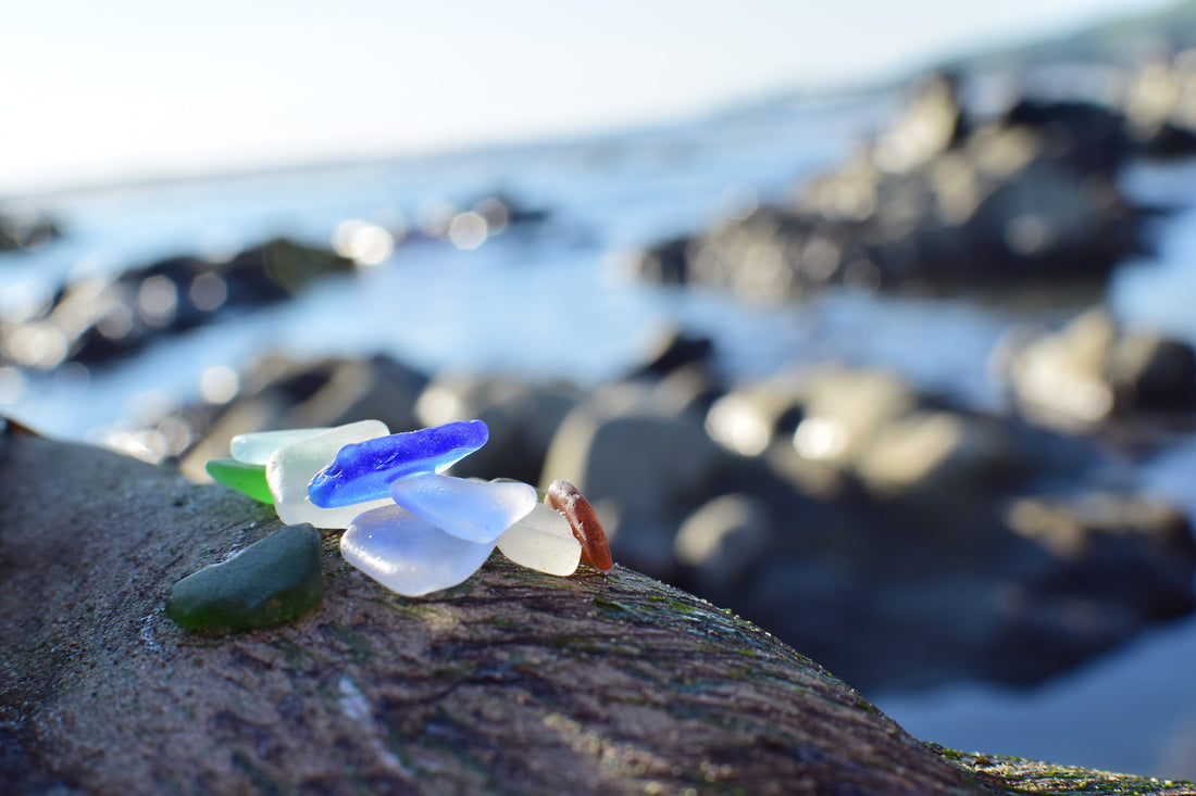 Colorful beach glass in front of rocks and water